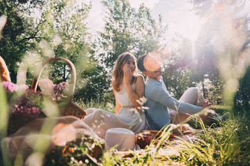 picnic for lovers. happy young couple spend time outdoors at sunset of the day. lovers have fun sitting on the bedspread in the forest. boy and girl on a romantic date at sunset
