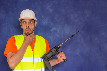 Male locksmith, builder. A worker with a tool in his hands and in working uniform.