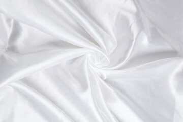 Obraz premium Colored white textile satin fabric folded in folds and waves with highlights and texture