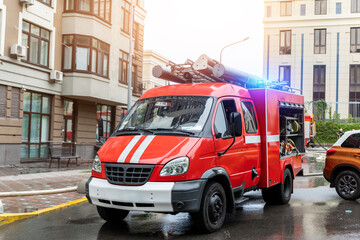 Small compact fire engine truck with ladder and safety equipment at accident in highrise tower residential apartment or office building in city center. Emergency rescue at disaster
