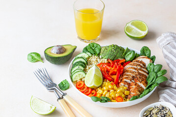 Healthy buddha bowl lunch with grilled chicken and bulgur, spinach, avocado, cucumber, bell pepper and corn on light background. Delicious balanced food concept.