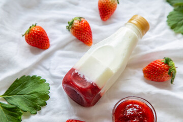 Hight angle views homemade strawberry milk with strawberry fruits on a white floor with leaf.