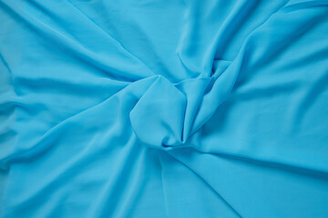 Colored blue textile satin fabric folded in folds and waves with highlights and texture