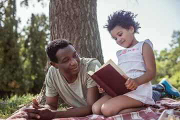 African american man and his kid reading a book together