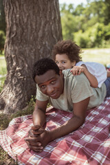 Curly-haired dark-skinned kid spending time with dad in the park