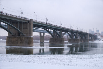 Photo  of the frozen Ob River with road and subway bridges on a winter snowy day. Novosibirsk, Russia.
