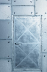 Background of silvery wall and door made of polyethylene foam sheets imitating metal with rivets.