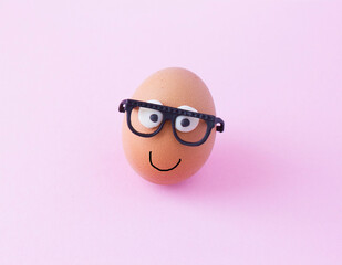 creative egg with glasses on pink background, happy easter concept.