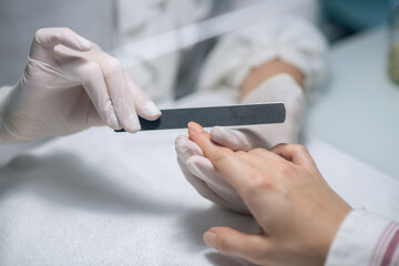 Close up picture of nail artists hands filing customers nails