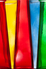 Bottles of bright, pure colors are in a row. Glass.