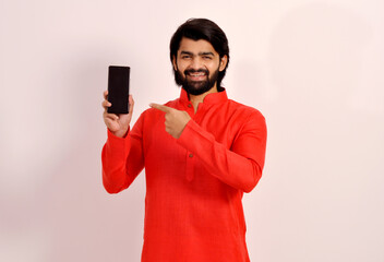 Smiling young man pointing at smartphone and looking at camera. Indian guy recommending product....