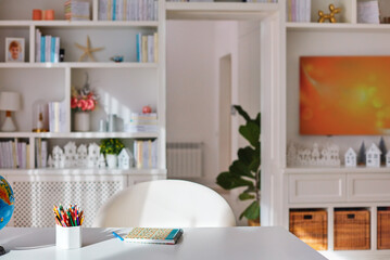 Fototapeta na wymiar sunlit cozy home office interior with wooden furniture, white desk with coloured pencils