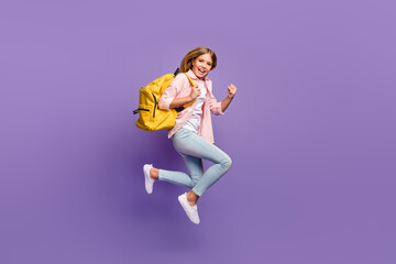 Fototapeta na wymiar Full size profile photo of hooray pretty girl jump run wear pink shirt jeans sneakers rucksack isolated on violet background
