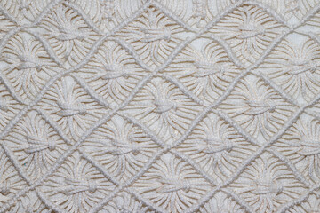 Solid background - a fragment of macrame products made of milk cream threads with rhombuses and square knots