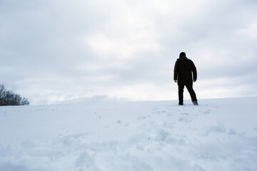A man in black clothes walking across a field of snow in winter time in Bavaria, Germany