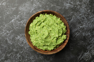Bowl of guacamole on black smokey background, top view