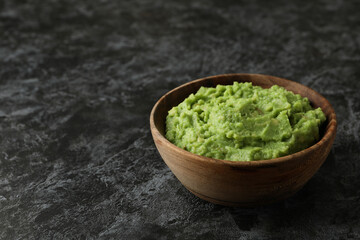 Bowl of guacamole on black smokey background, space for text