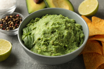 Concept of tasty eating with guacamole and ingredients on gray background