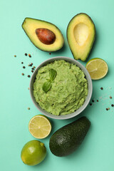 Concept of tasty eating with bowl of guacamole on mint background