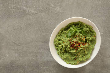 Bowl of guacamole on gray background, space for text