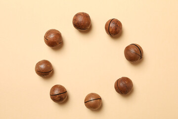 Tasty macadamia nuts on beige background, space for text