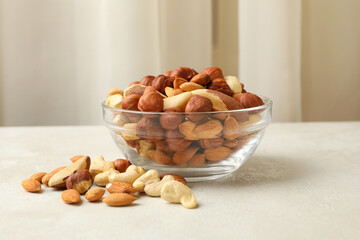 Fototapeta na wymiar Bowl with different nuts on white textured table