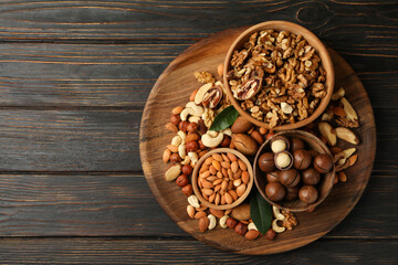 Tray with bowls with different nuts on wooden background