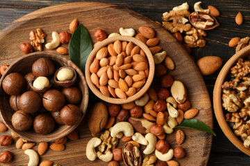 Tray with bowls with different nuts on wooden background