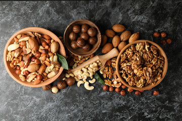 Bowl and wooden scoop with different nuts on black smokey background