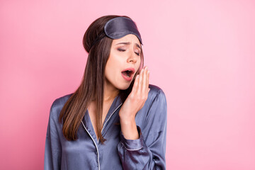 Photo portrait of sleepy girl yawning covering mouth with hand isolated on pastel pink colored background