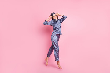 Full length body size photo of brunette in blue pajama jumping smiling touching sleeping mask...