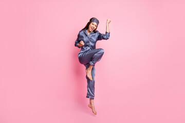 Full length photo portrait of celebrating woman jumping up isolated on pastel pink colored background
