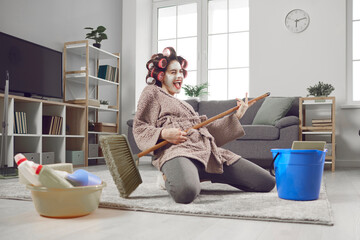 Cheerful young woman having fun and revealing hidden talent while cleaning house. Crazy housewife...