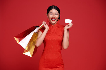 Happy Asian shopaholic woman wearing traditional cheongsam qipao dress holding credit card and...