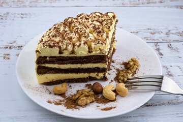 sweet nut dessert, chocolate puff cake, tiramisu, striped honey cake, a piece of cream cake on a white plate with nuts