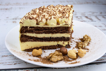 sweet nut dessert, chocolate puff cake, tiramisu, striped honey cake, a piece of cream cake on a white plate with nuts