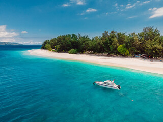 Fototapeta na wymiar Tropical island with beach, turquoise sea and white boat. Aerial view.