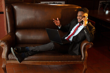 handsome young african man in suit indoors with mobile phone 