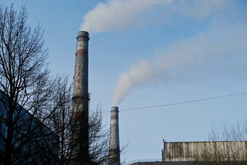 Almaty, Kazakhstan - 02.04.2021 : A smokestack and part of a heating plant building with trees