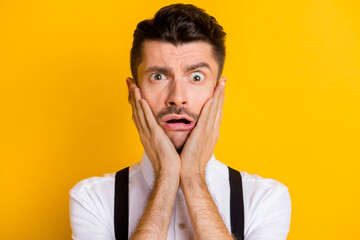 Photo portrait amazed stressed depressed man touching cheeks with hands staring problem trouble isolated on vibrant yellow color background
