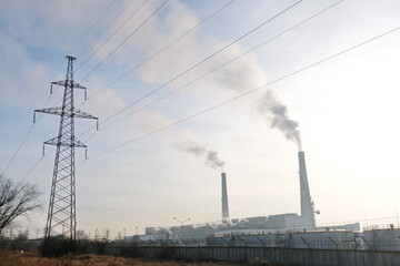 Almaty, Kazakhstan - 02.04.2021 : Power lines on the background of the building of the main heating plant with smoking pipes