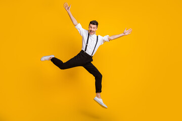 Fototapeta na wymiar Full length body size photo of jumping man dancing at party cheerful wearing suspenders isolated on vivid yellow color background
