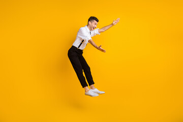 Fototapeta na wymiar Full length profile portrait of excited man jumping raise arms look empty space isolated on yellow color background