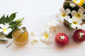 herbal healthy drinks ginger syrup cocktail water for health care with healthy fruits red apples for diet and white flower frangipani in basket arrangement flat lay style on background wooden white