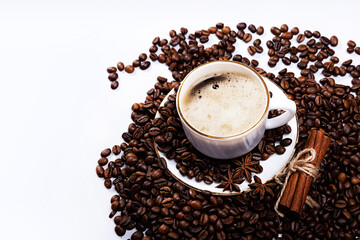 A cup of coffee whith coffee beans, cinnamon and anise star on a light background.