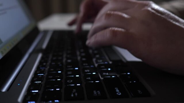 Woman freelancer fingers type on laptop keyboard under bright electric light in late evening at home covid pandemic isolation extreme closeup