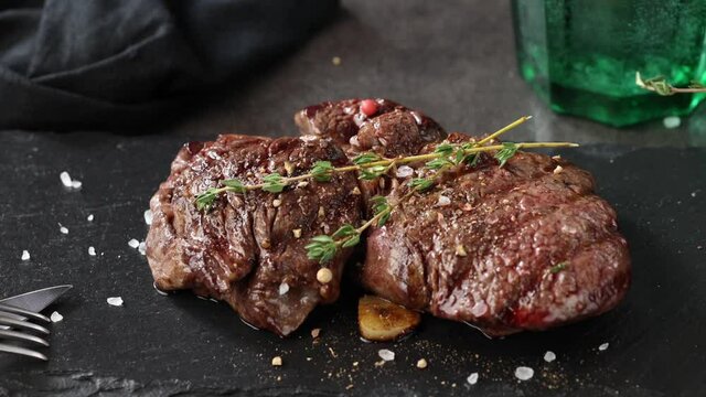 pepper falling on freshly grilled beef fillet steak meat on black stone restaurant plate