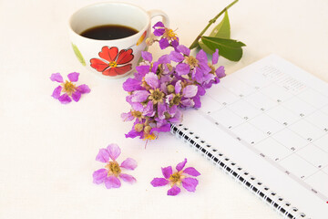 Obraz na płótnie Canvas hot coffee ,calendar planner and purple flowers in spring season arrangement flat lay style on background white 