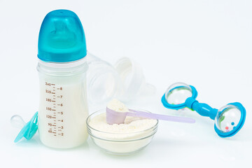 Composition with feeding bottle of baby milk formula on white table
