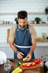 Portrait of handsome man in kitchen. Young man preparing salad